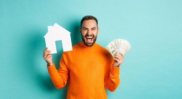 Real estate concept mortgage concept ecstatic caucasian man holding money dollars house make WEB